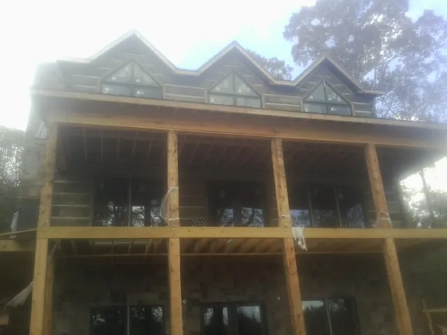 Dormers and porch framing on a large log home under construction — Roof Coating work by our crew in Randallstown