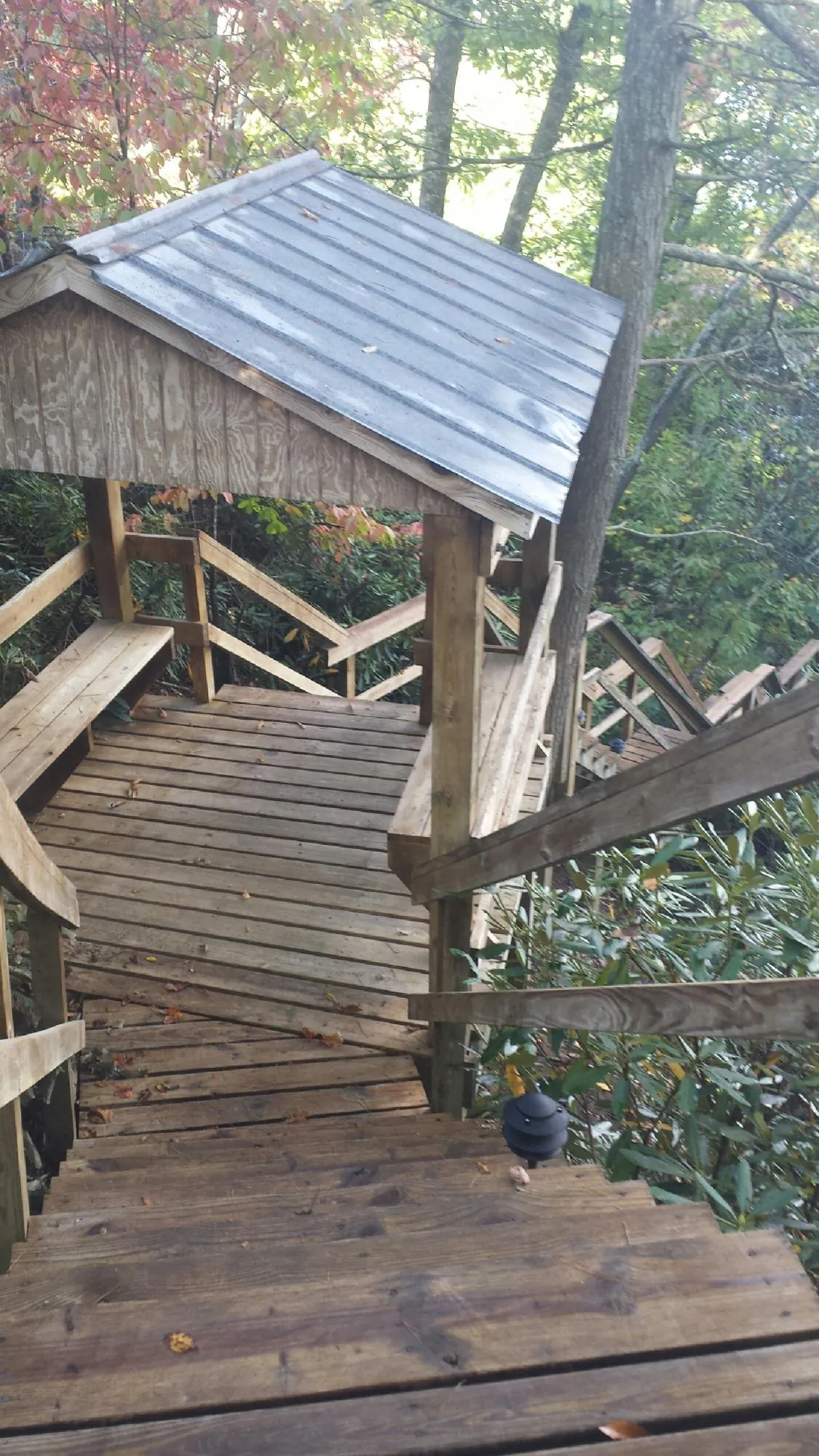 Metal roofed shelter over wooden steps on a wooded walkway — Skylight Repair & Installation work by our crew in Randallstown