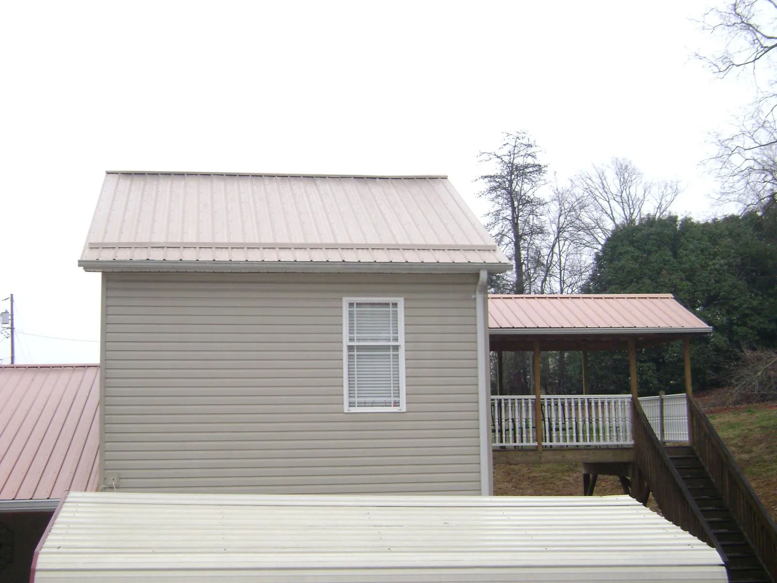 Tan metal roofs on a two story addition and attached porch, from a Roof Replacement job in Randallstown
