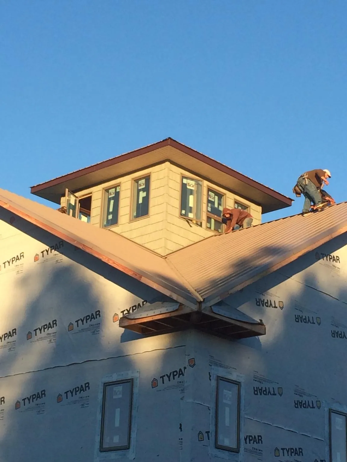Roofers working around a rooftop cupola on a new metal roof at sunset — Roof Waterproofing in Randallstown by Roofing Brothers